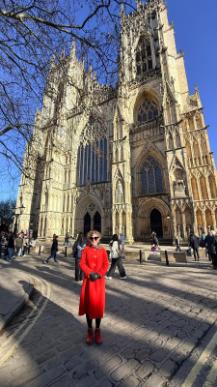 Tracey in a red coat in front of York Minster on a beautiful day